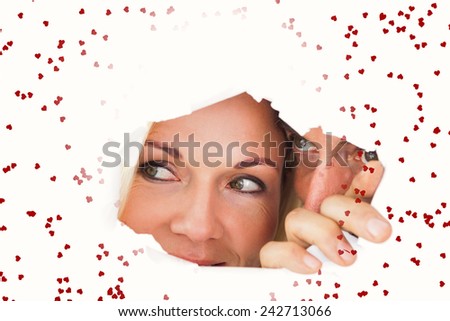 Couple looking through torn paper against red love hearts