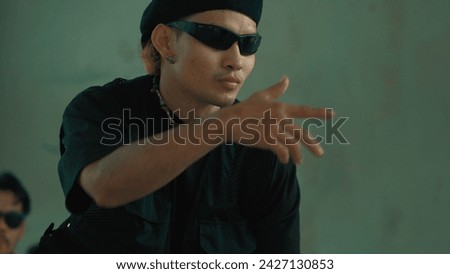 Closeup portrait of attractive asian hipster perform break dance at building with cement background. Handsome hip-hop dancer practice break dance and move arm or body. Outdoor sport 2024. Endeavor.