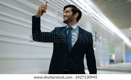 Happy manager receive good news from mobile phone with white background. Smiling project manager getting promotion, getting new job, winning while taking selfie at train station. Exultant.
