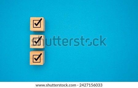 Three correct sign symbols on wooden cubes are over a blue background. Space for text. Checklist, Approved concept