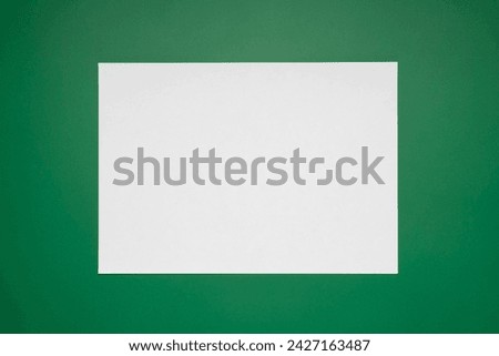 Empty white paper sheet isolated on green background