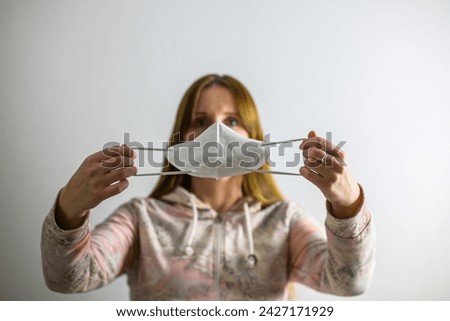 a woman puts a respirator on a shape. a sharpened respirator and a blurred shape - covid theme