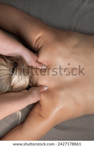 Top view of a woman undergoing a cervical-neck massage. Vertical photo.