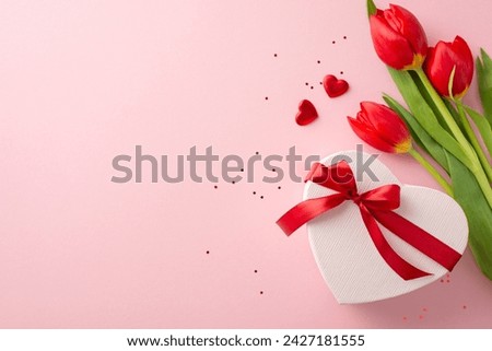 Ultimate girlish festivity scheme. Top view snapshot of a heart-shaped gift wrap, shimmer, little hearts, and a bouquet of tulips on a blush background, leaving margin for text or promotions