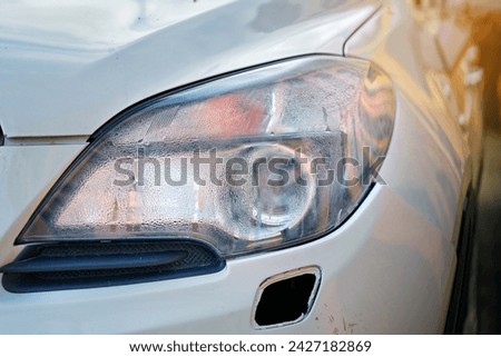Moisture in headlights, broken headlight after road collision. Condensation in headlights after road accident, wet front lamp. Car lamp with water inside. Fogged up headlight lenses, closeup Royalty-Free Stock Photo #2427182869