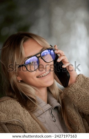 Portrait of cheerful, positive young woman with braces smiling looking at camera against blurred background. Smiling patient. Concept of beauty and medicine, dental care, malocclusion, orthodontic.
