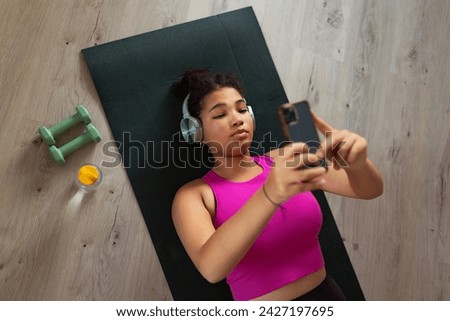 Woman resting after home workout, New Year's resolutions, healthy lifestyle, losing weight and selfcare. Concept of morning or evening exercise. Royalty-Free Stock Photo #2427197695