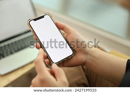 Young man sitting in front of laptop and using mobile phone. Blank empty screen for your text