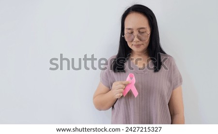 Portrait picture of happy Asian woman with pink ribbon, great for prevention breast cancer concept. Copy space.