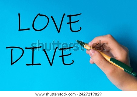 Children hand with pen write on an blue white background. Writing hand. Word Love Dive