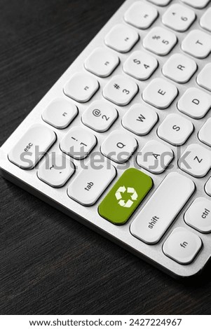 Recycling symbol on green computer keyboard key, selective focus