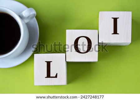 LOI (LETTER OF INTENT) - acronym on wooden big cubes on green background with cup of coffee. Total market value of the investments that a person or entity manages on behalf of clients.