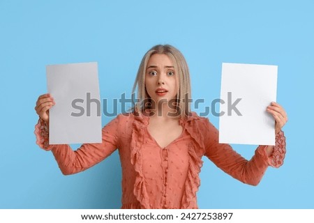 Young woman with blank paper sheets on blue background