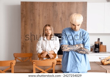 Offended young man with his girlfriend in kitchen