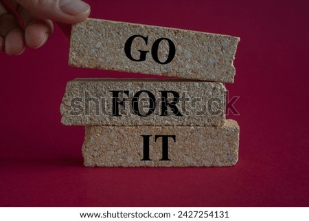Male hand placing a block with word go on top of a blocks tower with words go for it. Beautiful red background. Copy space. Business concept. Royalty-Free Stock Photo #2427254131
