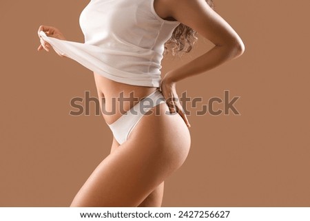 Beautiful young African-American woman with stretch marks on her body against beige background, closeup