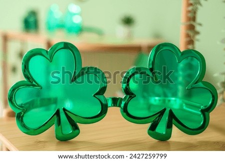 Clover shaped novelty glasses on wooden shelf, closeup. St. Patrick's Day celebration
