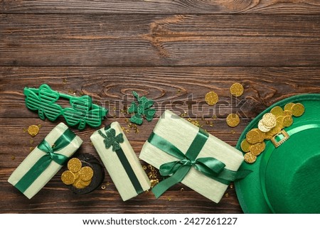 Gift boxes with leprechaun hat, pot of golden coins and plastic eyeglasses for St. Patrick's Day celebration on wooden background