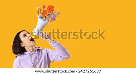 Young woman shouting into megaphone with drawn flowers on yellow background Royalty-Free Stock Photo #2427261639