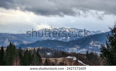 Dramatic dark gray clouds over the Vysoky Verkh mountain in the Ukrainian Carpathians. Panoramic view. Background with winter mountain landscape in February messenger. Real photo, not fake, not AI