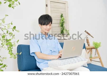 Asian young man using the laptop in the living room