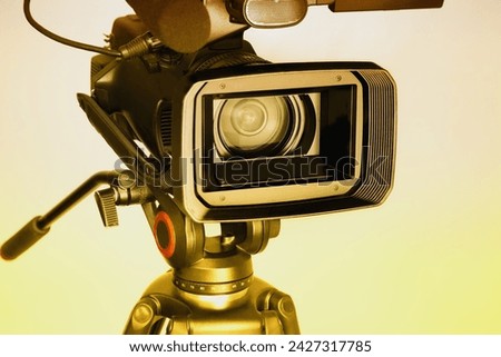 Video camera on a white background with a wide lens in warm light, professional video shooting, video shooting with a professional camera