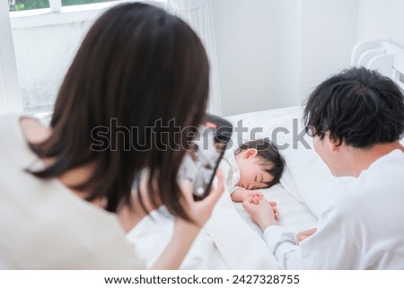 young asian couple taking photo with smartphone baby sleeping in bed