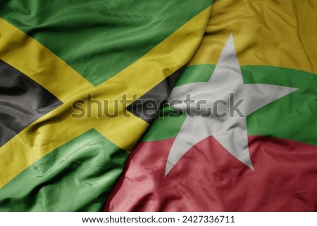 big waving national colorful flag of myanmar and national flag of jamaica . macro