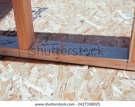 Post beam stud timber framing with marker on OSB sub flooring sheets cover, attach to joists with wood screws Oriented Strand Board plywood, new house construction, interior wall framing, Texas. USA Royalty-Free Stock Photo #2427338025