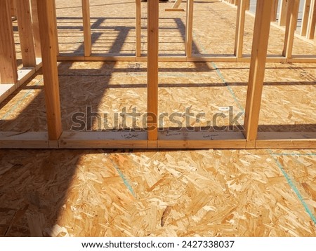 OSB sub flooring sheets cover, attach to the joists with wood screws Oriented Strand Board plywood, timber framing with posts beams studs of new house construction, interior wall framing, Texas. USA Royalty-Free Stock Photo #2427338037
