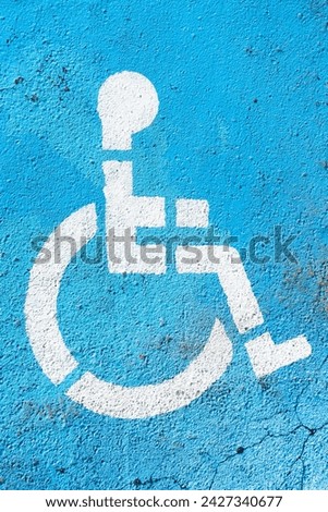 Disabled parking background. Asphalt blue paint. Wheelchair icon painted white. Parking space. Outdoor car park spot. Handicap access. Transportation sign.