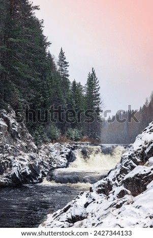 Kivach Falls on a snowy winter day. Vertical landscape photo with cascade waterfall. Suna River, Kondopoga District, Republic of Karelia, Russia