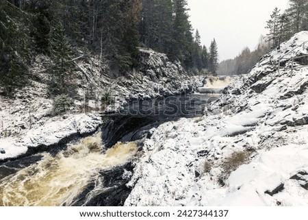 Snowy cascade waterfall. Landscape photo of Kivach Falls on a cold cloudy winter day. Suna River, Kondopoga District, Republic of Karelia, Russia