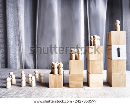Wooden toy doll on high pedestal and many other figures below. Concept of leadership, which is not available to everyone. Victory and the winner. Talent, Recruitment employee and Successful business Royalty-Free Stock Photo #2427350599