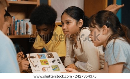 Caucasian smart girl listening young highschool boy talking about book at modern library. Group of student with mixed races reading picture book while lying down on floor in a circle. Edification.