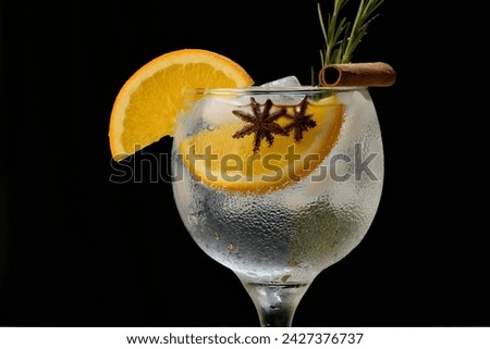 Gin and tonic cocktail with orange, cinnamon, rosemary and star anise on a black background Royalty-Free Stock Photo #2427376737
