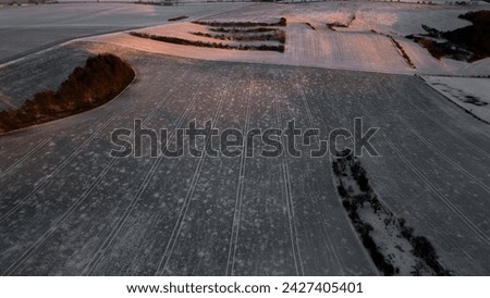 Snowy landscape at sunset, small town, road between fields