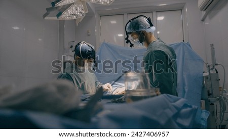 Team of two doctors men surgeons processing surgical operation using endoscopic medical instruments in sterile operating room hospital emergency surgery procedure with anesthesia saving patient life