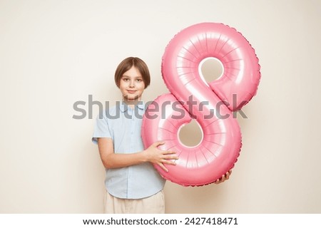 Cheerful happy child with balloon number 8. Smiling boy on white background, rejoices spring holiday. Women's Day on March 8th