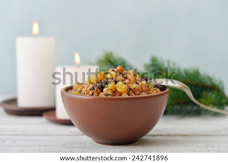 Traditional Christmas slavic dish kutia in ceramic bowl with spoon and candles