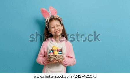 Cute little child wearing bunny ears on Easter day. Girl with painted eggs. Royalty-Free Stock Photo #2427421075
