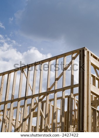 Stock photo of the wood frames of a new urban housing development under construction against a blue sky with white clouds.