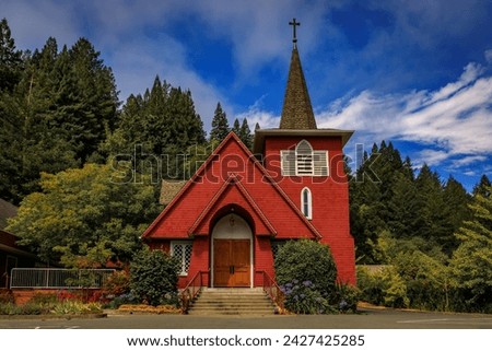 Restored red facade of Saint Philip the Apostle, Roman Catholic Church in Occidental, rural Northern California with a green forest in the background Royalty-Free Stock Photo #2427425285