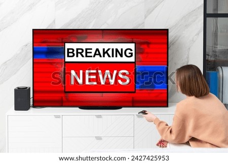 Back view on excited man sitting on the couch and watching breaking news on tv at home	 Royalty-Free Stock Photo #2427425953