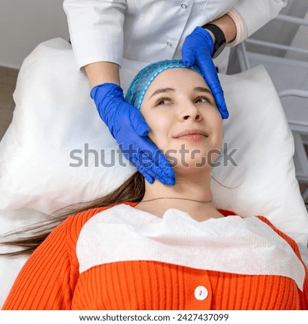 Cosmetologist putting hands on client's face, preparing for beauty procedures. Calm model lying on cosmetic chair with eyes open, waiting for facial massage. Skin care concept. Horizontal photo