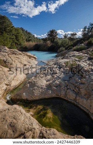Vertical photo of the source of Fuente Caputa, Mula, Region of Murcia, Spain, between rocks and on a sunny day,
