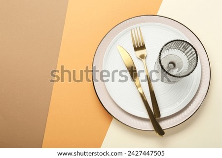 Ceramic plates, glass and cutlery on color background, top view. Space for text Royalty-Free Stock Photo #2427447505