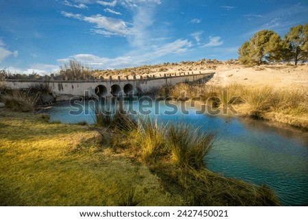 Horizontal photo of the source of Fuente Caputa in the town of Mula, Region of Murcia, Spain, with a bridge in the background, on a sunny day