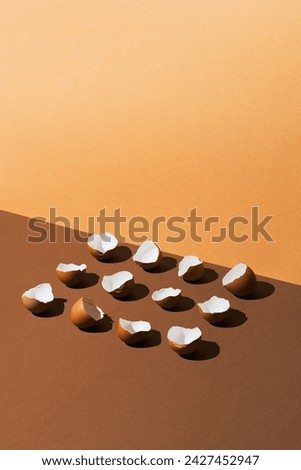 Egg shells aligned in a row, flat lay on brown background. High angle view studio shot with high contast and sharp shadows.