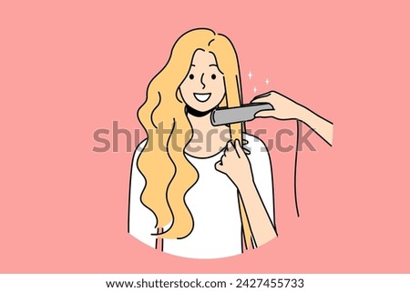 Woman at hairdresser appointment using hair straightener to straighten curls before party or date. Happy blonde girl visits hairdresser or stylist who helps change image and become more beautiful Royalty-Free Stock Photo #2427455733